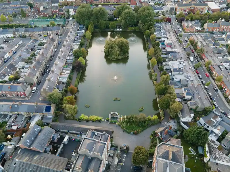 Aerial view of the Blessington Street Basin in Dublin 7, a rectangular pond with a wooded island, surrounded by terraced streets.